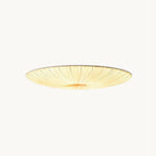 This Clérachic flush ceiling light on a plain backdrop: a wide, shallow beige fabric shade with fine pleats gathered to the centre and lit warm.