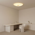 Clérachic fabric ceiling light in a pale minimalist study, above a curved white desk and a small cream armchair.