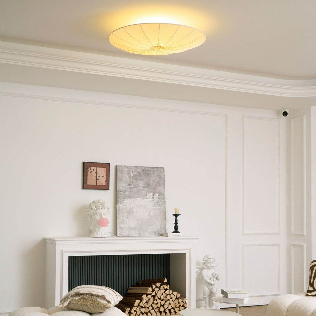 Clérachic fabric ceiling light glowing above a white panelled room with a fireplace stacked with logs and a framed abstract print.