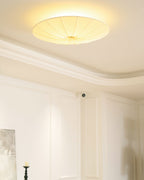 Lit Clérachic pleated ceiling light with a halo on a coffered ceiling, above panelled white walls.