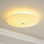 Clérachic fabric ceiling light seen from the side, lit, with a halo behind the rim and a crown moulding at the left.