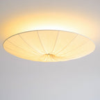 Clérachic pleated ceiling light lit with a bright halo, its gathered centre and wide rim seen from below.