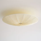 Unlit Clérachic fabric ceiling light seen from below, with a cream textured shade and a small metal canopy on a white ceiling.