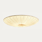 Largest Clérachic pleated ceiling light on a pale grey backdrop, lit warm, its fine folds fanning wide from the centre.