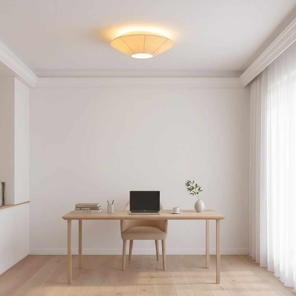Clérachic pleated ceiling light glowing above a home office with a light wooden desk, a laptop and sheer curtains at the window.