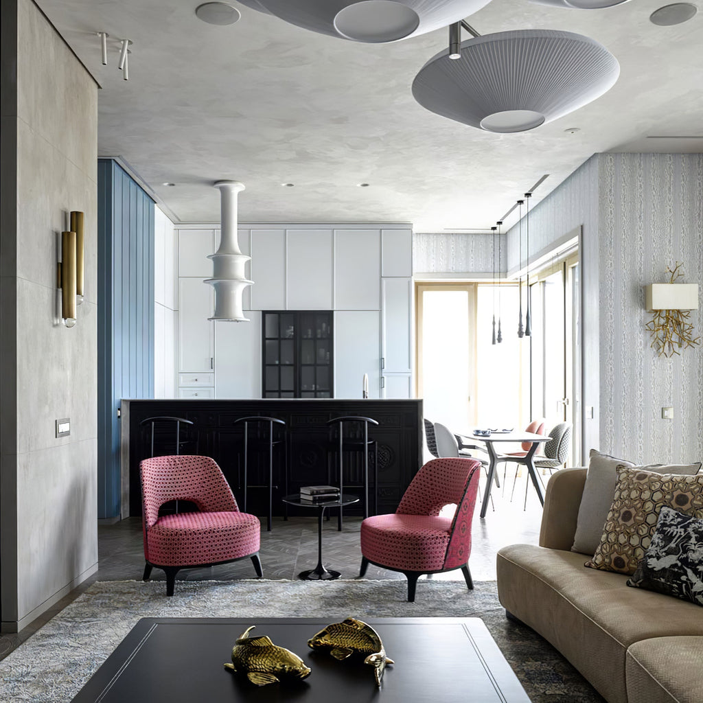 Several grey-toned Clérachic pleated ceiling lights across a high ceiling above an open-plan lounge with pink armchairs.