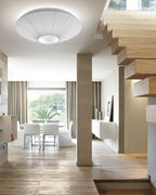 White Clérachic pleated ceiling light above a staircase with floating wooden treads, with a dining table by a window beyond.
