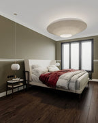 Clérachic pleated ceiling light in cream above a bedroom with an olive wall, a dark wood floor and a bed with a red throw.