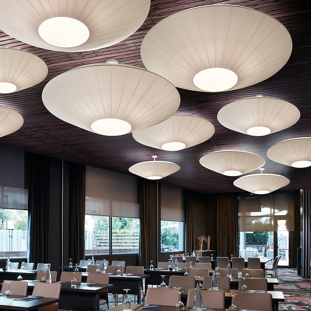 Close view of a group of large Clérachic pleated ceiling lights in white, hung from a dark timber ceiling over a conference room.