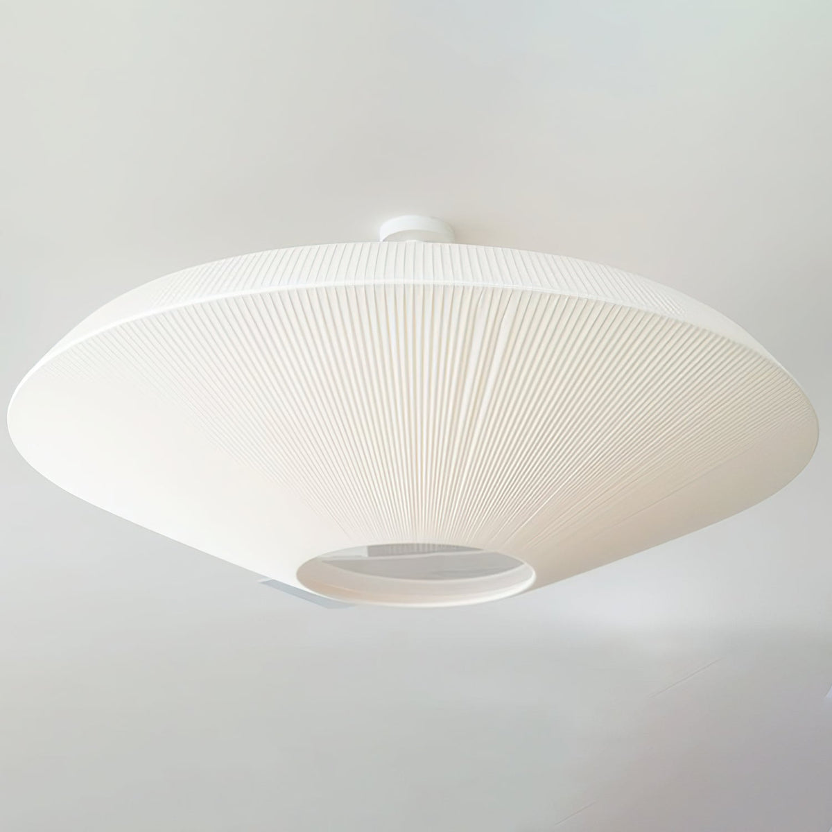 Close angled view of a white Clérachic ceiling light with a short mounting stem, and the diffuser opening at the centre.