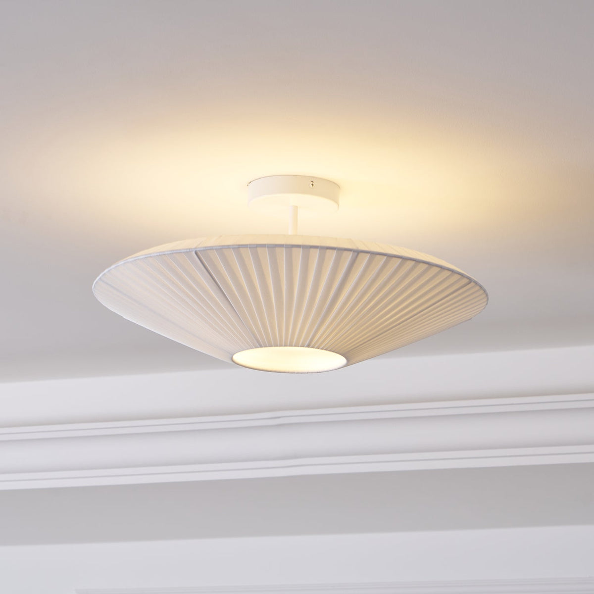 Clérachic white pleated ceiling light on a short stem, glowing warm above a moulded cornice.