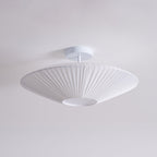 A white Clérachic pleated ceiling light on a white stem and round canopy, seen from below against a pale grey ceiling.