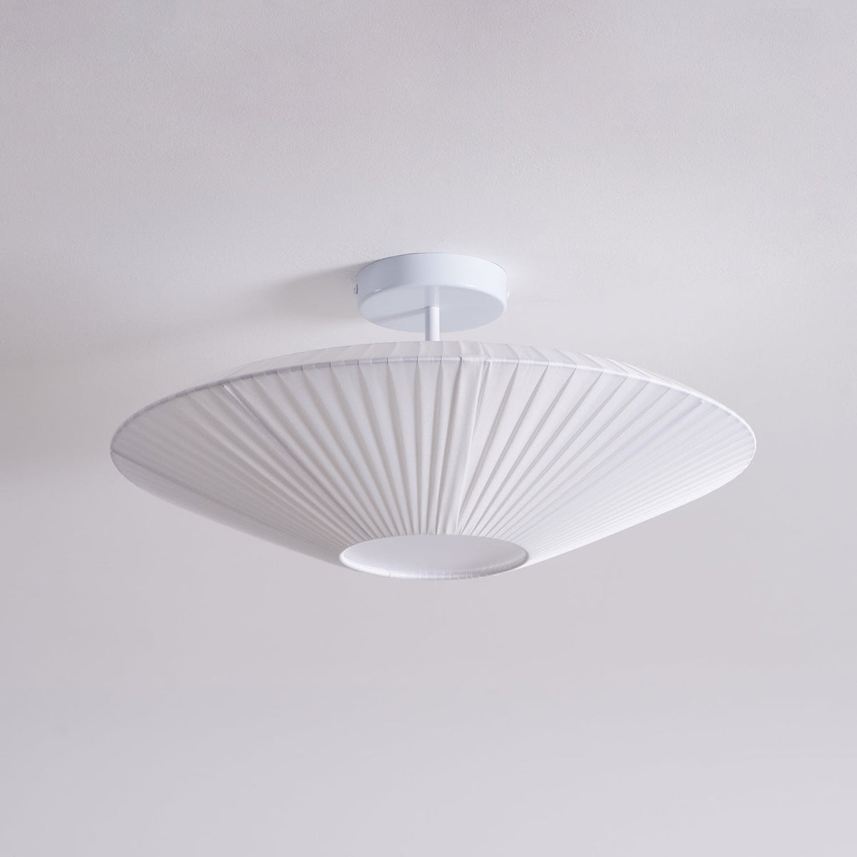 A white Clérachic pleated ceiling light on a white stem and round canopy, seen from below against a pale grey ceiling.
