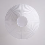 View from directly below at the pleated white shade and the round white diffuser of this Clérachic ceiling light.