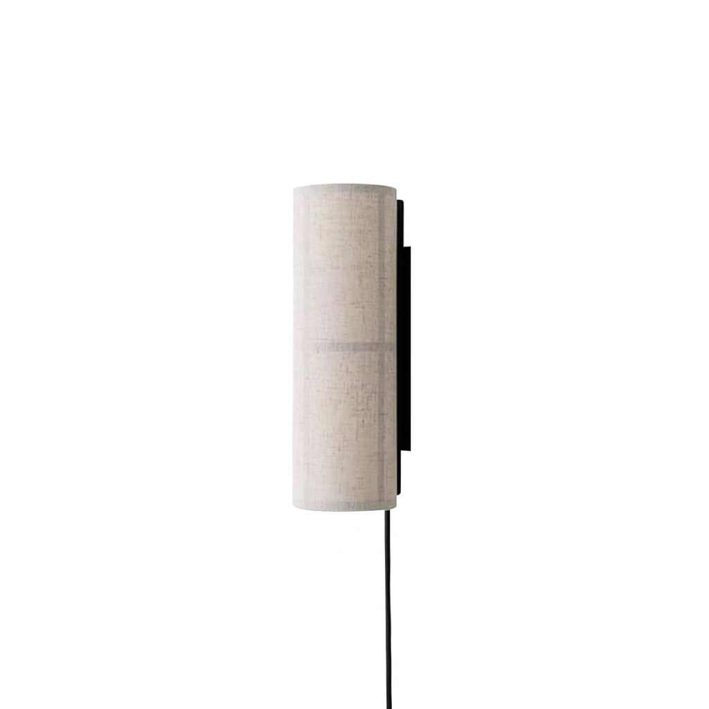 Grey linen Clérachic cylinder wall light, unlit, seen from the side on white, its black back plate and cord clear.