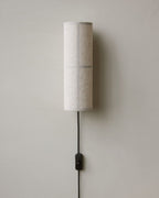 Clérachic grey linen wall light on a pale wall, with a black inline push-button switch on its cord below the shade.