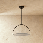 Clérachic black steel arch pendant with a pleated white fabric disc, switched off and hung on a rod from a plaster ceiling.