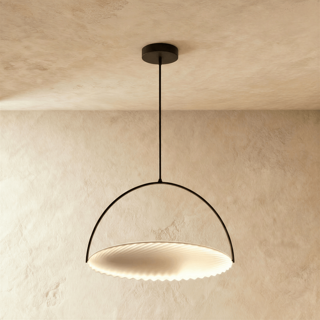 Clérachic largest black arch pendant with a broad pleated white disc lit from within, hung on a rod against plaster.