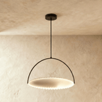 Clérachic largest black arch pendant with a broad pleated white disc lit from within, hung on a rod against plaster.