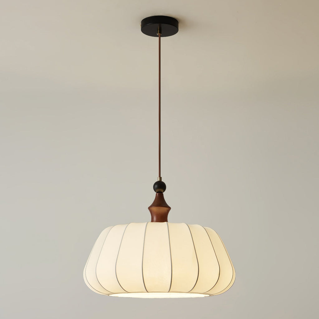 This Clérachic pendant hangs by a single cord from a black round canopy, with its walnut-colour wood top and pleated fabric dome.