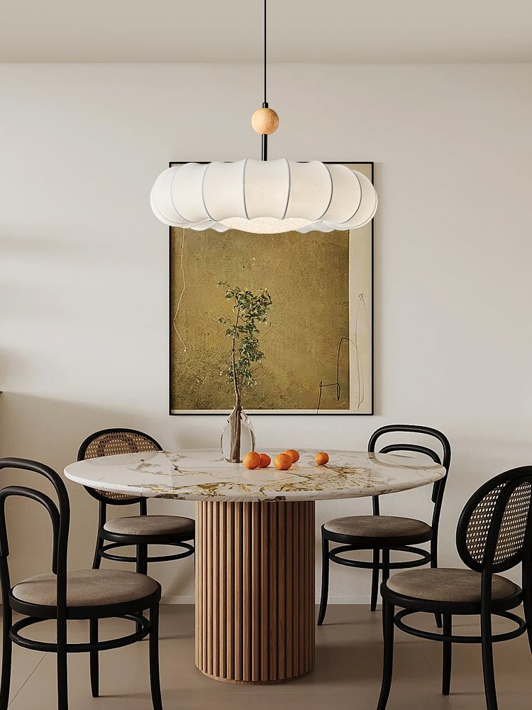 Clérachic fabric pendant light over the marble dining table, framed against a painting of a single potted branch.