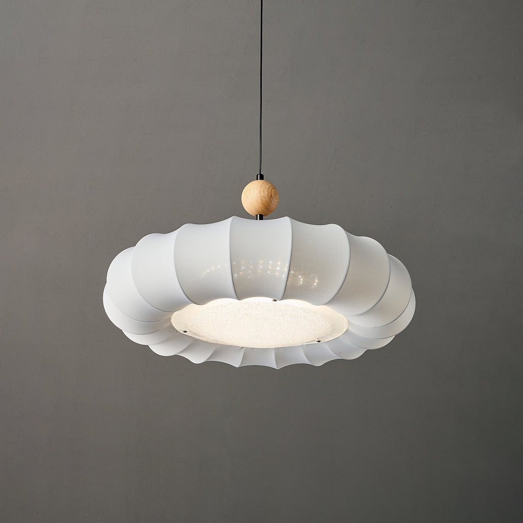 Clérachic fabric pendant light seen from below, its bright recessed disc ringed by small fixings and framed by the panel tips.