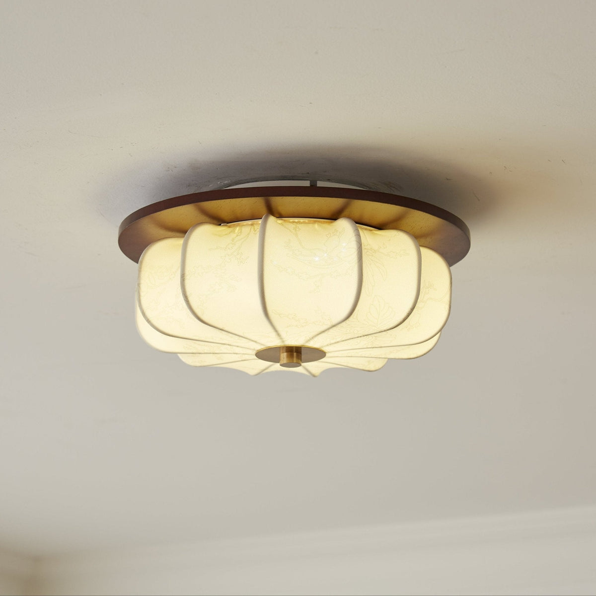 A Clérachic ceiling light with a walnut rim and ribbed fabric shade glows softly against a pale ceiling, seen from below.
