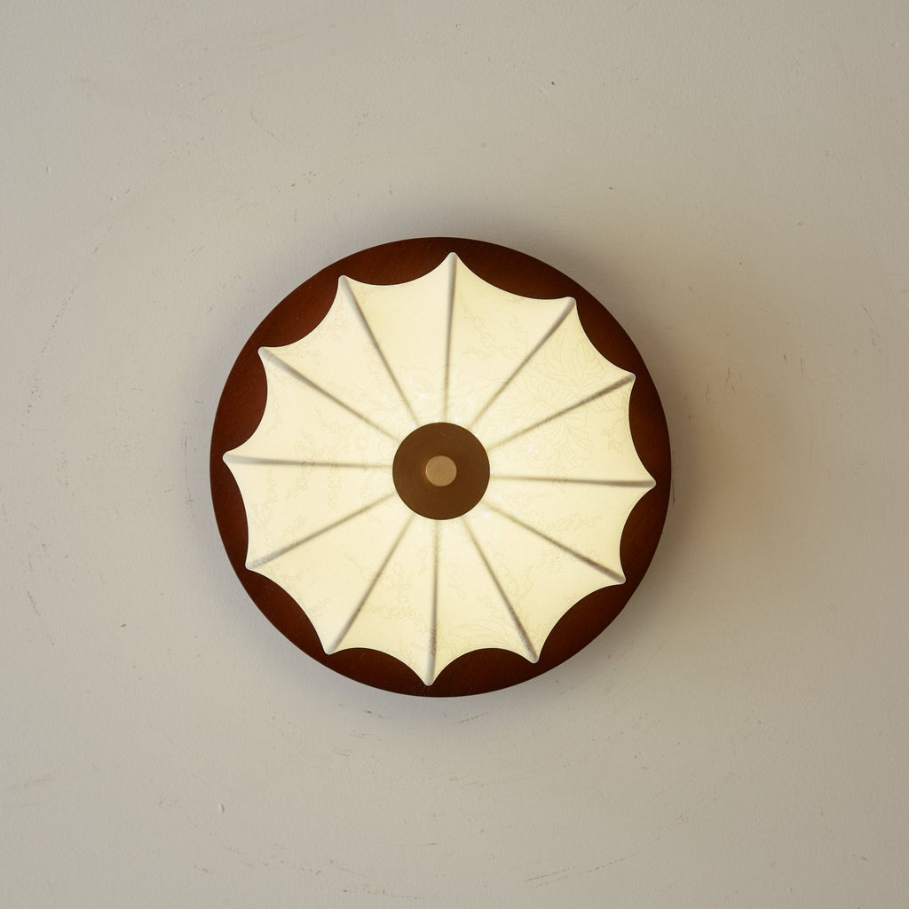 View straight up at this Clérachic ceiling light, showing the walnut disc and fan-like ribs of the fabric shade.