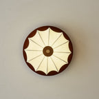 View straight up at this Clérachic ceiling light, showing the walnut disc and fan-like ribs of the fabric shade.