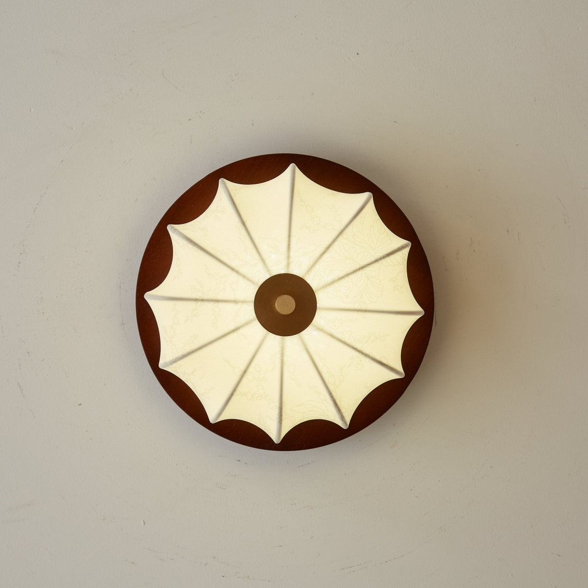 View straight up at this Clérachic ceiling light, showing the walnut disc and fan-like ribs of the fabric shade.