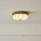 Fabric lotus shade on a Clérachic ceiling light with a walnut rim and a lit, ribbed fabric shade, set flush against a white ceiling.