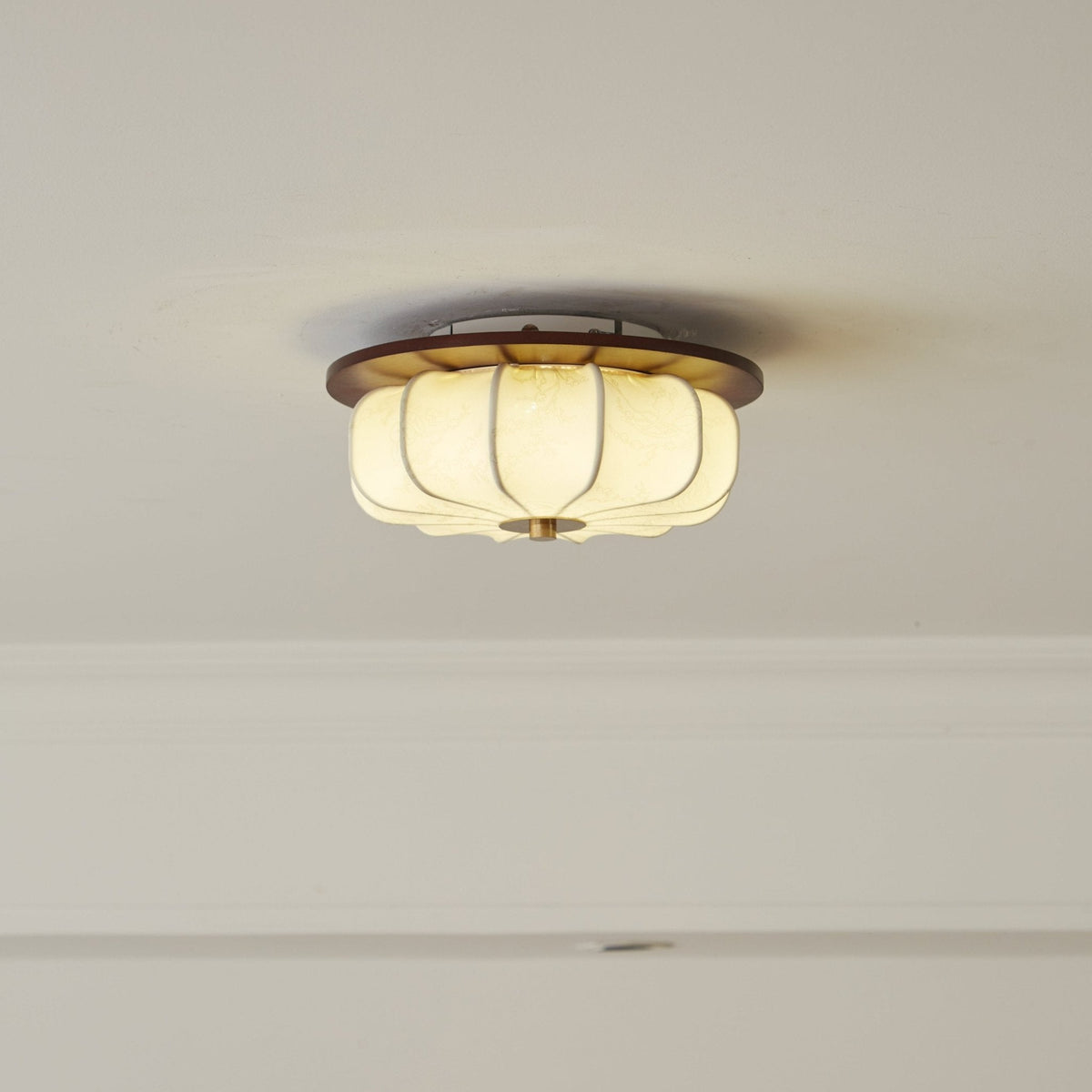Fabric lotus shade on a Clérachic ceiling light with a walnut rim and a lit, ribbed fabric shade, set flush against a white ceiling.