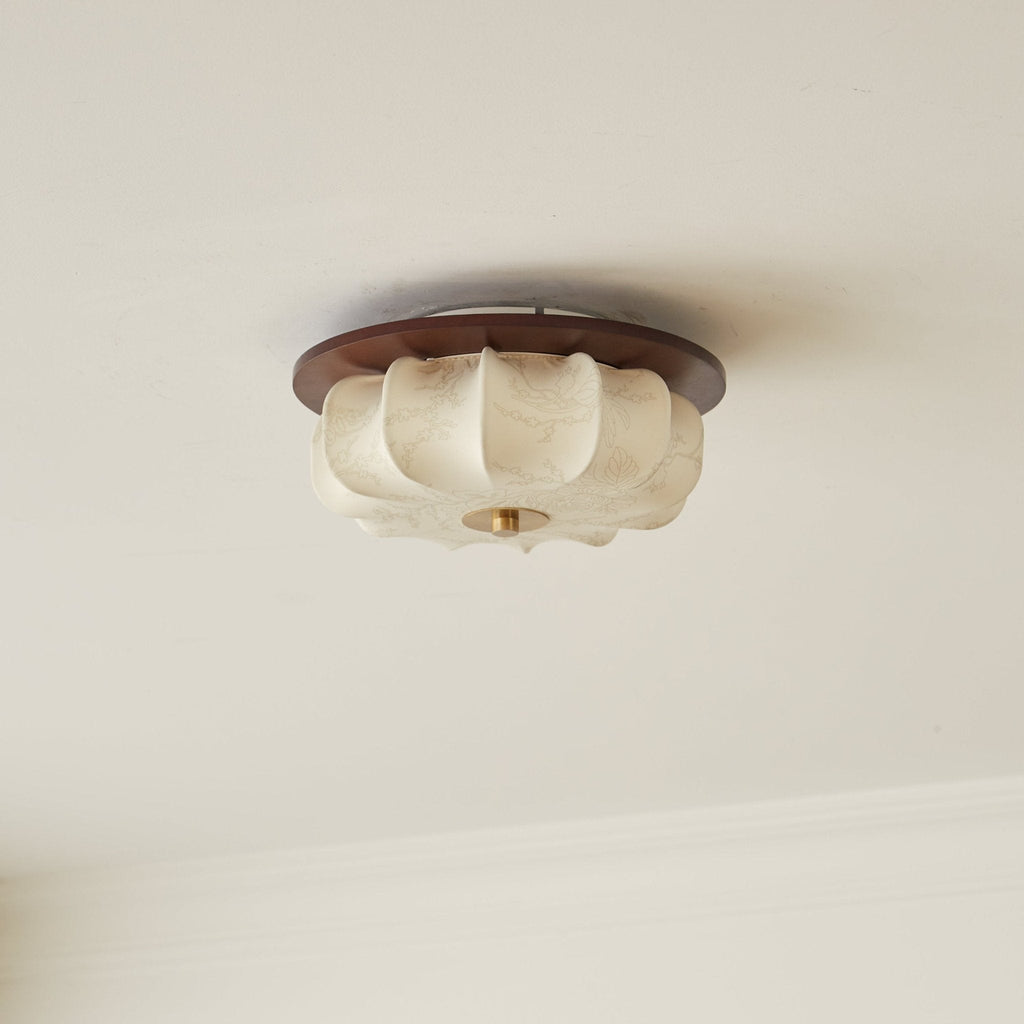 An unlit Clérachic fabric ceiling light in cream, with a walnut rim and brass cap, against a pale ceiling.