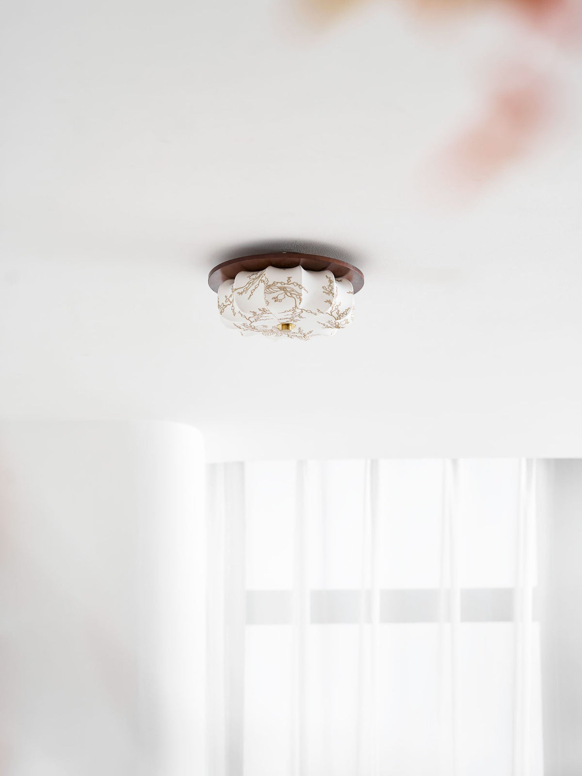 Lit Clérachic ceiling light with a floral-etched fabric shade and walnut rim, seen small above a sheer curtain.