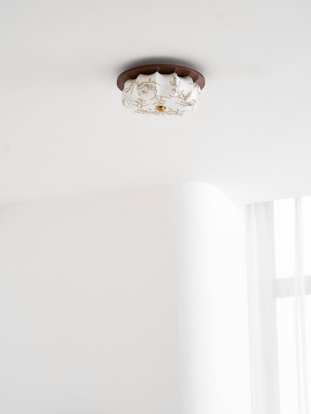 A small Clérachic ceiling light with a floral-etched fabric shade and walnut rim, against a white ceiling.