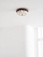 A small Clérachic ceiling light with a floral-etched fabric shade and walnut rim, against a white ceiling.