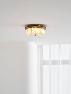 A lit Clérachic ceiling light with a floral-etched fabric shade and a walnut rim, near a window with sheer curtains.