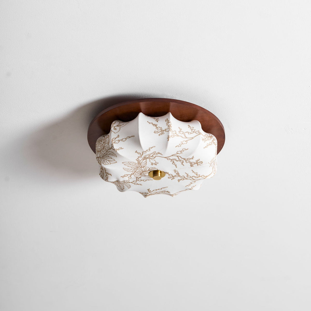 Walnut-rimmed Clérachic ceiling light with a walnut rim and a floral-etched fabric shade, seen at an angle on a white ceiling.