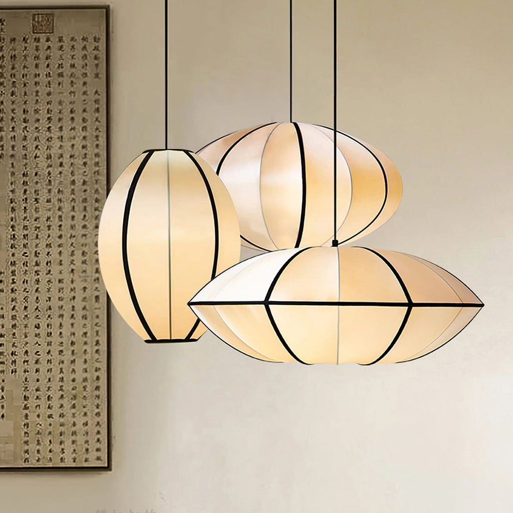 Three lit fabric pendants in different shapes hang together beside a framed calligraphy scroll, their black ribbing clear, from Clérachic.