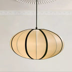 A wide, flattened fabric pendant with bold black ribs hangs from a black cord below a decorative plaster ceiling rose, from Clérachic.