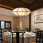A white fabric pendant with a pointed edge hangs over a round banquet table in a room with a dark timber ceiling, from Clérachic.