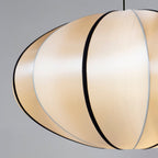 Close view of the fabric panels and black ribs on this Clérachic pendant, with a soft glow through the cloth.