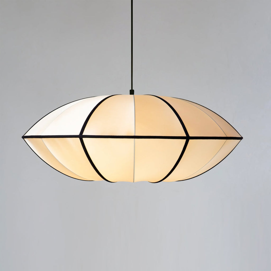 A wide fabric pendant with a pointed rim and black ribs hangs on a black cord against a plain grey backdrop, a Clérachic pendant.
