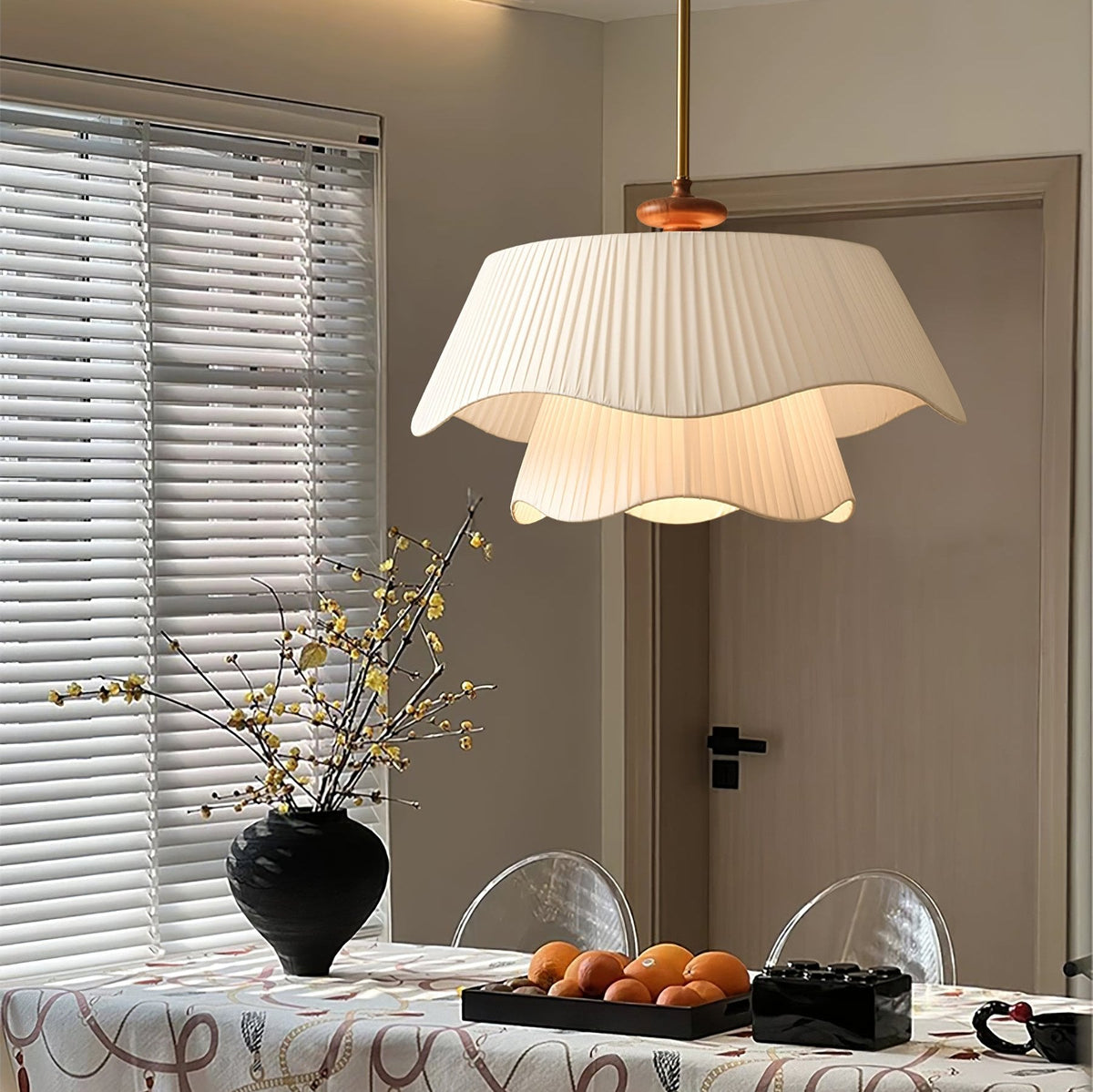A Clérachic pendant over a dining table set with oranges and a black vase, with venetian blinds and a door in the background.
