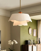 Clérachic pendant lit in a room with olive-green walls, a small oval mirror, white orchids and a sideboard below.
