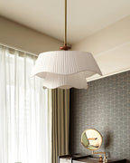 Angled view of the Clérachic pendant beside a window with sheer curtains, a patterned grey wall and a round mirror.
