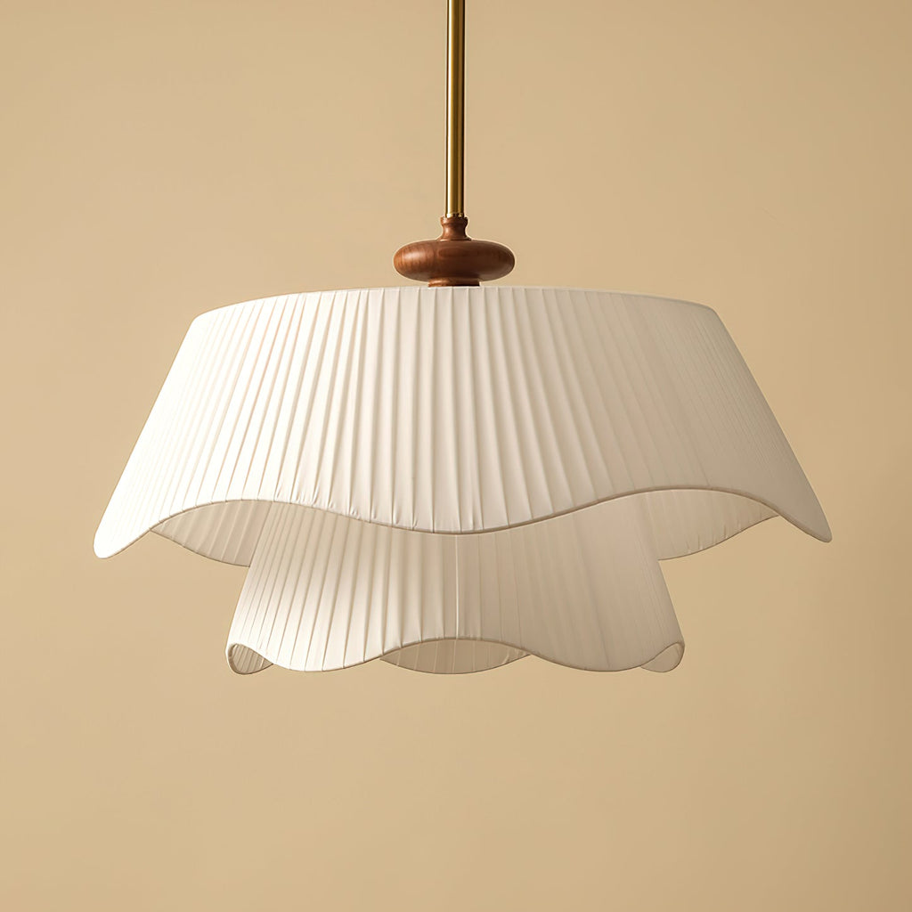 Close view of the pleated fabric folds and wavy hem on this Clérachic pendant, with its dark wooden bead and gold stem.
