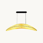 This Clérachic pendant on a plain white backdrop, a long leaf-shaped fabric shade with pleats and a black oval ceiling plate above.