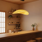 In a warm timber-lined room with paper-screen windows, a Clérachic pendant hangs near shelves of bottles above a wooden counter.