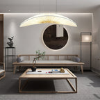 Above a low wooden table and a daybed, a Clérachic pendant with a cream pleated shade hangs near a round mirror.
